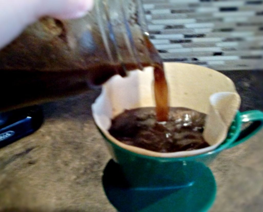 Cold Brew coffee in a Mason Jar being strained into a coffee filter