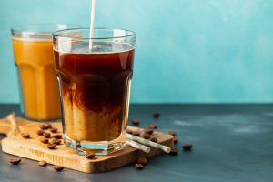 glasses of cold brew coffee with milk and coffee beans on a wooden board.
