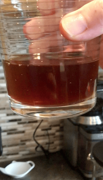 glass of cloudy cold brew coffee being held up to the camera by a hand